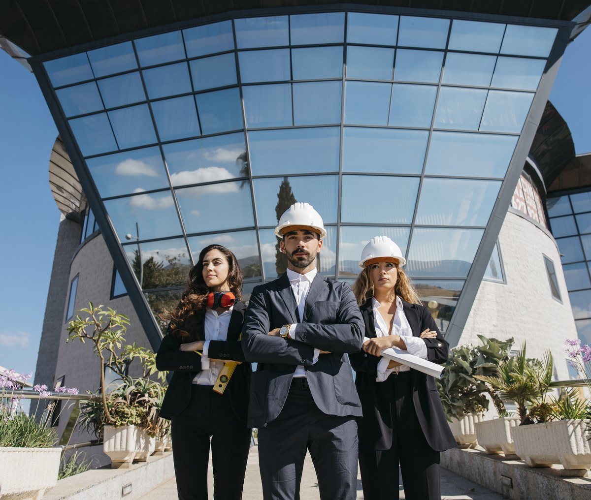Construction professionals in hard hats in front of a modern glass building